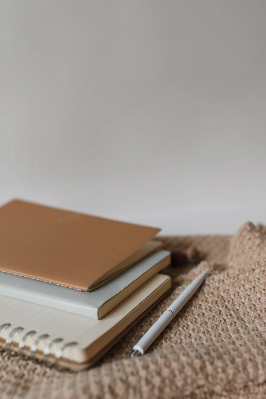 Hardcover journals stacked on a knitted throw