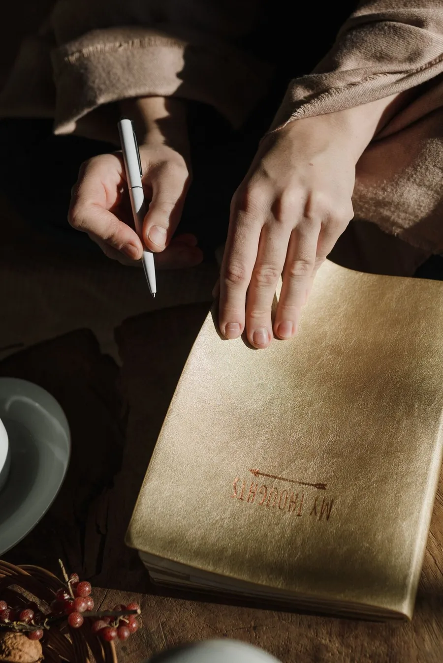 Hands lettering a tan journal cover